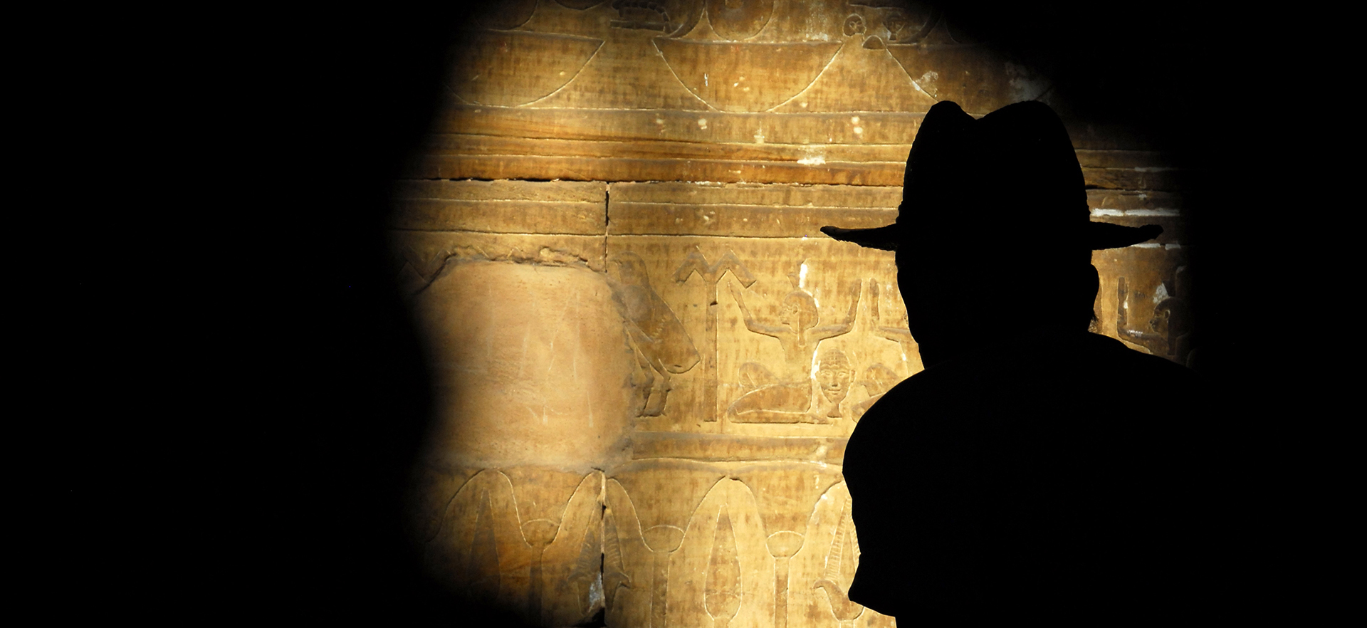 Silhouette d’un voyageur devant les bas-reliefs d’un temple égyptien